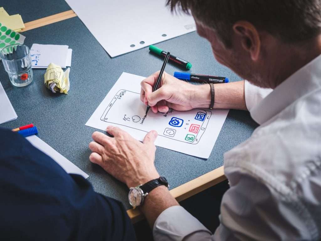 Singapore technology partner Close-up of hands sketching a mobile app layout on paper at a desk