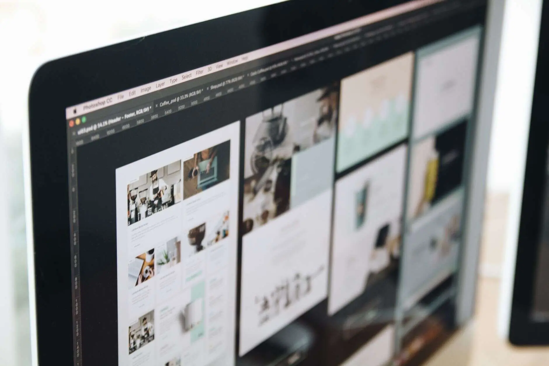 Website page layouts open in a design tool on a large monitor